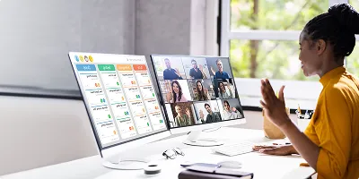 A professional woman using multiple monitors for a video conference
