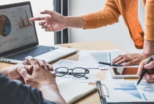 Three business professionals collaborating and analyzing data on a laptop